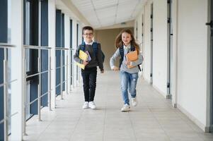 estudante com o saco da escola e livros dentro a escola. Educação conceito. costas para escola. aluno indo para aula. à moda Garoto com mochila. Garoto pronto para estude foto