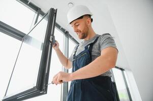 serviço homem instalando janela com Chave de fenda foto