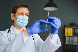 fechar-se mão do mulher médico ou cientista dentro médico uniforme vestindo face mascarar protetora dentro laboratório segurando remédio líquido vacinas frasco garrafa, coronavírus ou covid-19 conceito. foto