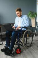 jovem feliz empreendedor dentro cadeira de rodas trabalhando em computador portátil às casa foto