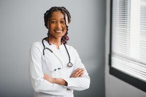 retrato confiante africano fêmea médico médico profissional escrevendo paciente notas isolado em hospital clínica corredor janelas fundo. positivo face expressão. foto