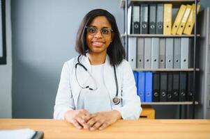 retrato confiante africano fêmea médico médico profissional escrevendo paciente notas isolado em hospital clínica corredor janelas fundo. positivo face expressão. foto