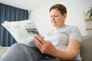 mulher sentado lendo a jornal às lar. foto