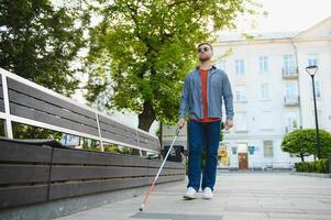 fechar-se do uma cego homem em pé com branco bastão em rua foto