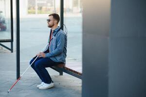 cego homem esperando para ônibus às uma ônibus estação foto