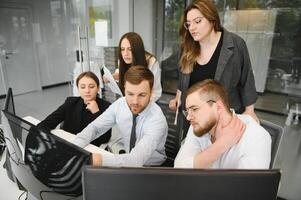 sorridente o negócio pessoas sentado às uma escrivaninha dentro frente do uma computador portátil computador foto