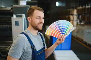 engraçado retrato do tipógrafo em pé com cor amostras às a impressão fabricação foto