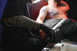 profissional tatuagem artista faz uma tatuagem em uma jovem homem mão foto