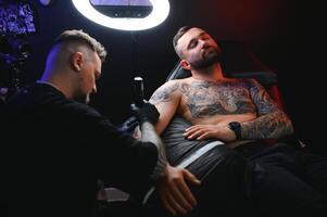 retrato do uma tatuagem mestre mostrando uma processo do criação tatuagem em uma mão debaixo a luminária luz foto