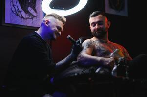 tatuagem artista demonstra a processo do obtendo Preto tatuagem com pintar. mestre trabalho dentro Preto estéril luvas foto