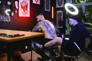 tiro do uma tatuagem artista e uma mans costas totalmente tatuado com Preto tinta foto