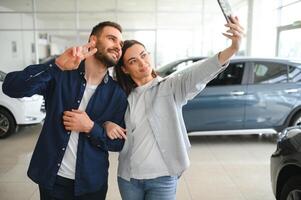 primeiro grande Comprar junto. retrato do uma feliz jovem casal abraçando dentro uma carro salão foto