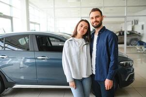 feliz jovem casal escolhe e comprando uma Novo carro para a família. visitando a concessionária foto