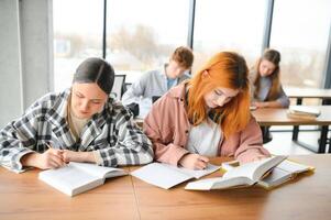 teste. fechar-se do jovem alunos sentado dentro uma linha e tendo teste dentro seus livros de teste foto