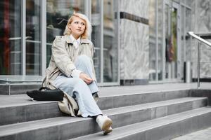 jovem lindo bonita menina caminhando ao longo a rua com Bolsa e copo do café. foto