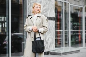 jovem lindo bonita menina caminhando ao longo a rua com Bolsa e copo do café. foto