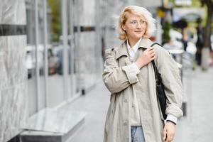 jovem lindo bonita menina caminhando ao longo a rua com Bolsa e copo do café. foto