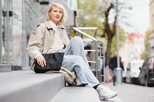 jovem lindo bonita menina caminhando ao longo a rua com Bolsa e copo do café. foto