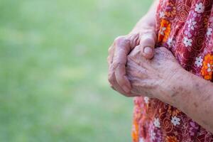 fechar-se do enrugado mãos Senior mulher enquanto em pé dentro uma jardim. ter esperança, fé. conceito do envelhecido pessoas e religião foto