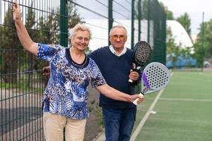 retrato do desportivo em forma Senior mulher jogando padel em aberto quadra em verão dia, pronto para bater bola. saúde e ativo estilo de vida conceito.. foto