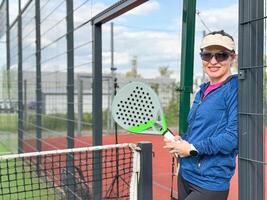 mulher jogando padel dentro uma verde Relva padel quadra atrás a internet foto