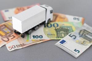 branco brinquedo caminhão em euro notas. conceito para logística, transporte e e finança foto