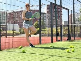 retrato do ativo emocional mulher jogando padel tênis em aberto quadra dentro verão, oscilante raquete para Retorna bola sobre internet .. foto