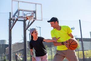 uma feliz pai e adolescente filha jogando basquetebol lado de fora às tribunal. foto