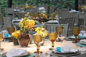 sofisticado almoço mesa configuração dentro iate clube com pratos, copos, flores e talheres foto