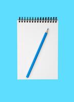 uma em branco caderno e uma azul lápis em uma azul fundo. flatlay composição. topo visualizar. foto
