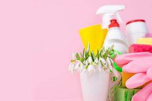 Primavera flores, detergentes e limpadores para limpeza a casa em uma Rosa fundo. Primavera limpeza. cópia de espaço. fechar-se. foto