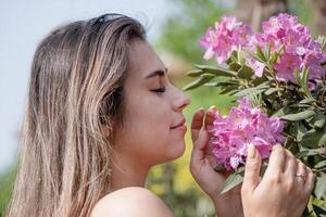 lindo jovem mulher vestindo branco verão vestir cercado de Rosa rododendro Flor foto