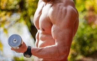 muscular jovem corpo fazer bíceps exercício. sem camisa desportivo masculino corpo. foto