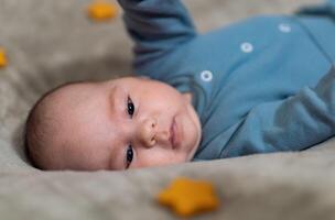 recém-nascido bebê Garoto dentro luz azul roupas. bebê mentiras em dele costas e faz uma doce face foto
