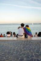 gay casal com arco Iris bandeira relaxante em passeio perto mar foto