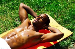 jovem em forma africano americano homem não camisa dentro Sol foto