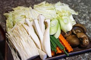 fechar acima sortido fresco legumes preparado para shabu shabu japonês quente Panela- alface, cenoura, alho-poró, shitake, rei ostra e dourado agulha cogumelo foto