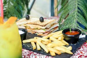 sanduíche e francês fritas em de madeira mesa foto
