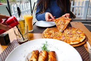 mulher desfrutando uma fatia do pizza às uma restaurante foto
