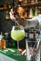 barman derramando uma coquetel para dentro uma caule vidro foto