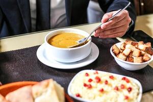 homem de negocios desfrutando uma tigela do sopa dentro uma formal terno foto