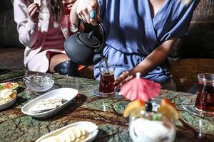 grupo do mulheres sentado por aí uma mesa com bebidas foto