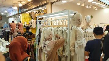 Jacarta, Indonésia - marcha 23, 2024, ásia muçulmano mulheres olhando às muçulmano roupas durante Ramadã às uma muçulmano moda loja. foto
