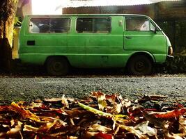 Surakarta cidade, central Java, Indonésia, abril 15, 2024 vintage cenário do uma verde velho e clássico minivan carro estacionamento em a lado do a estrada dentro a manhã. oxidado automóvel abandonado em a rua foto