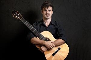 jovem modelo com bigode posando com dele guitarra em neutro fundo foto