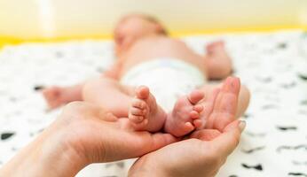 recém-nascido bebê pés. fofa pés do dormindo bebê. mães mãos foto