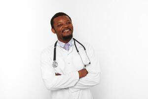 sorridente médico barbudo preto cruzou os braços em jaleco branco com estetoscópio, fundo branco foto