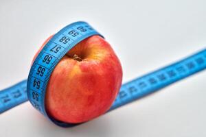 maçã vermelha com fita métrica isolada no fundo branco foto
