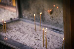 espalhados velas brilhando com uma dourado amarelo luz dentro a areia, cópia de espaço foto