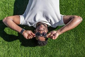 homem deitado em Relva segurando oculos de sol foto